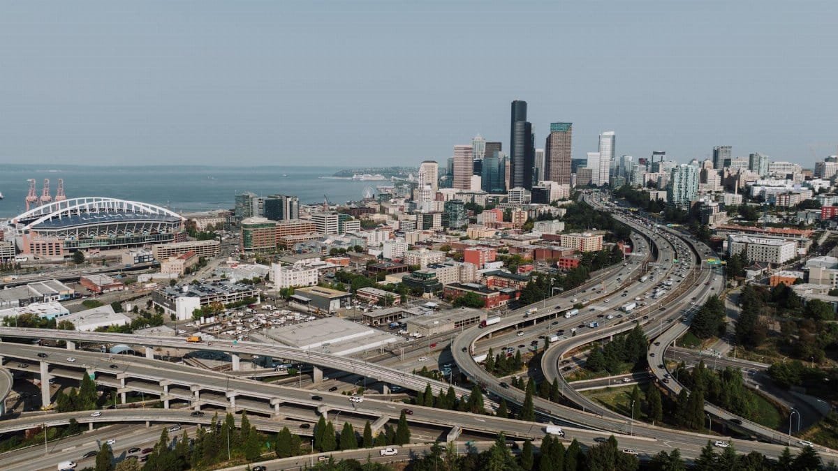 Aerial view of Seattle's downtown skyline with highways and waterfront on a clear day.