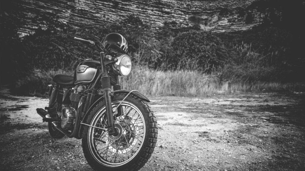 Classic Triumph motorcycle parked outdoors in a black and white setting, exuding vintage charm.