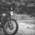 Classic Triumph motorcycle parked outdoors in a black and white setting, exuding vintage charm.