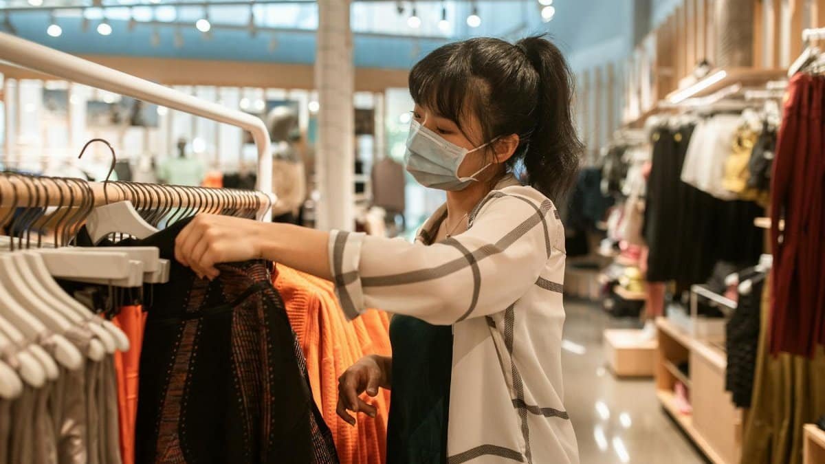 Woman wearing a face mask shopping for clothes in a department store.