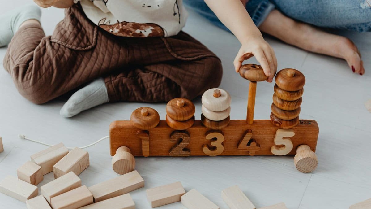 A child engaging with wooden educational toys, counting blocks indoors.