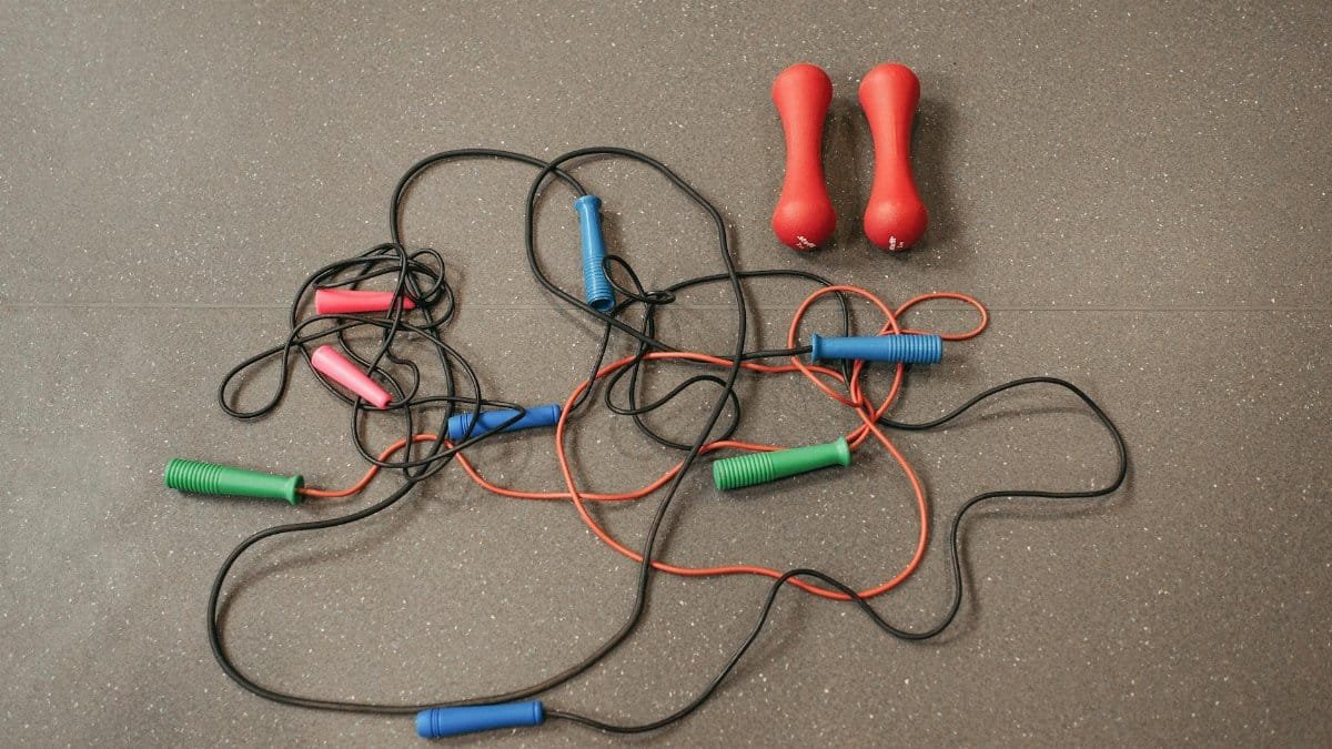 Vibrant jump ropes and dumbbells on a gym floor, perfect for home workouts.