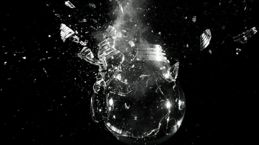 A dramatic image of a light bulb shattering into pieces against a dark background.