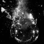 A dramatic image of a light bulb shattering into pieces against a dark background.