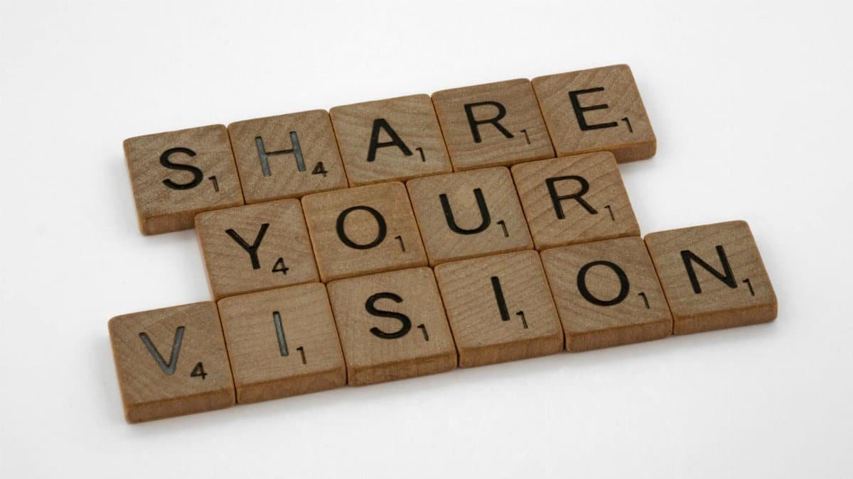 Scrabble tiles forming the inspiring phrase 'Share Your Vision' on a white background.