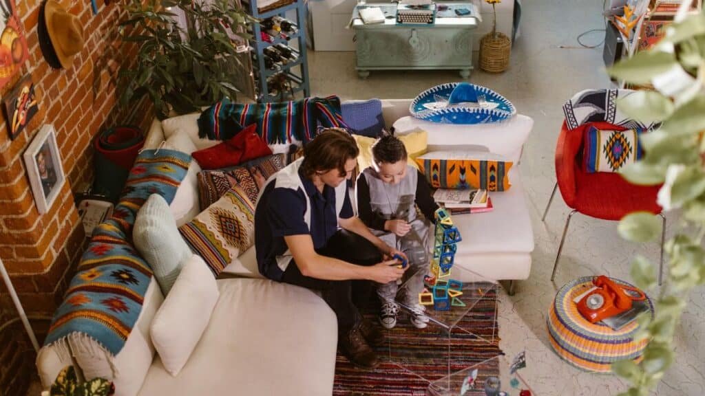 A father and son bond through play with colorful magnetic blocks in a cozy living room setting.