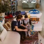 A father and son bond through play with colorful magnetic blocks in a cozy living room setting.