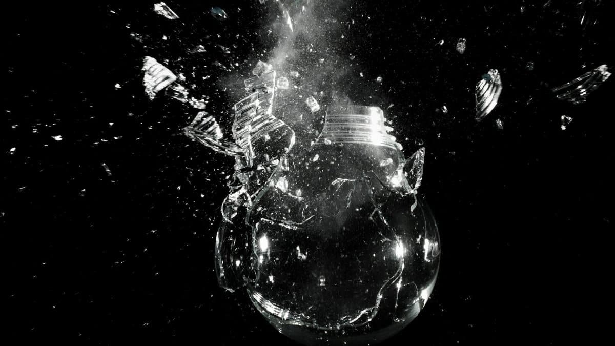 A dramatic image of a light bulb shattering into pieces against a dark background.