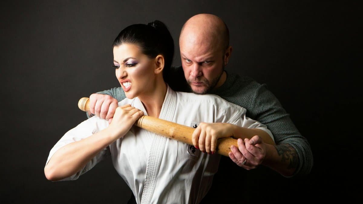 Martial arts training session showing self-defense techniques with a wooden stick.