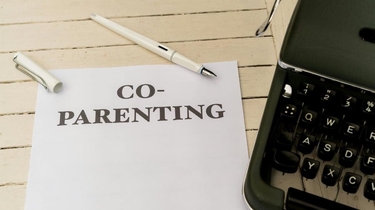 Co-parenting paper and pen on a white wooden table next to a typewriter.