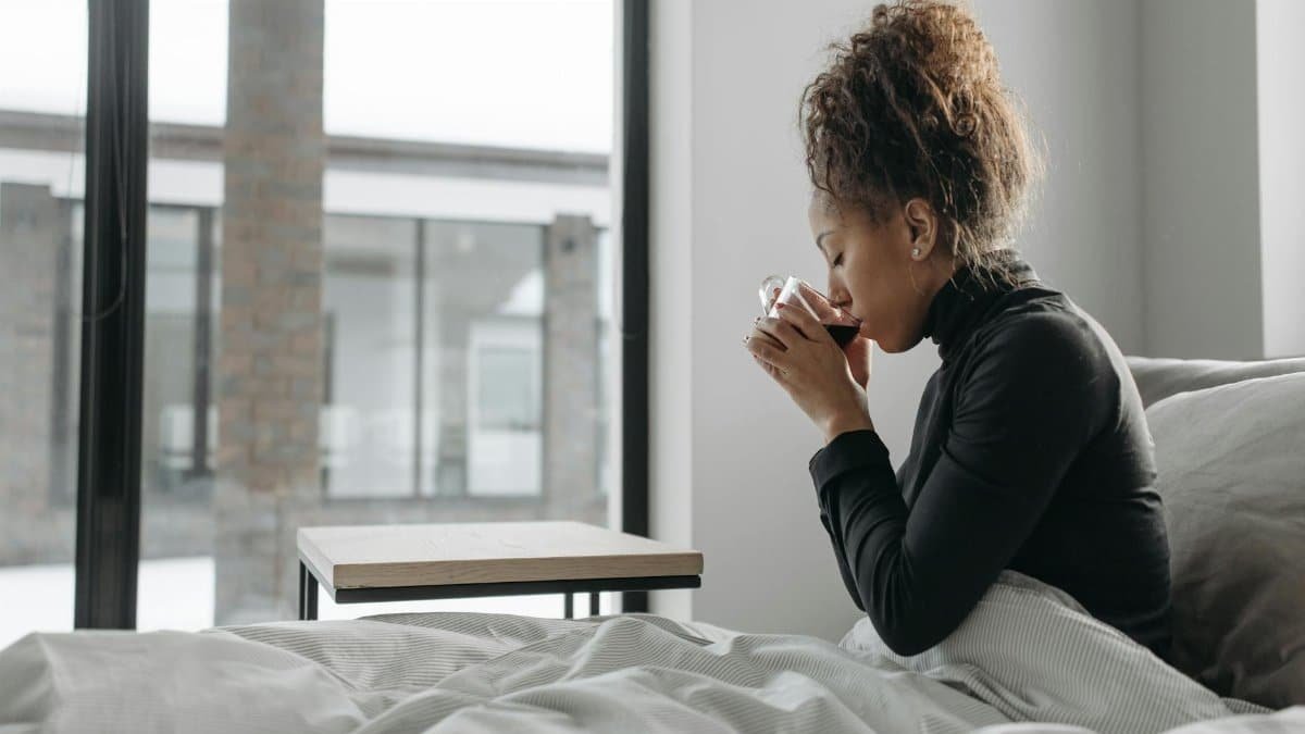 A woman enjoys a warm drink indoors, providing a cozy and relaxed atmosphere.