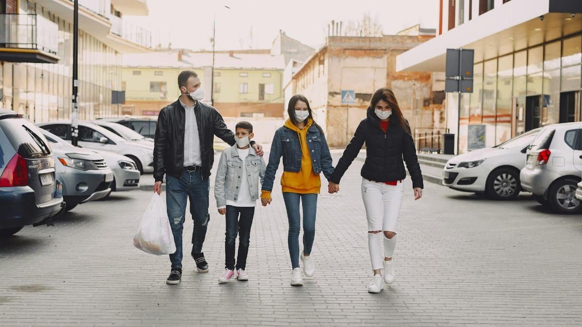 A family of four walks outdoors wearing masks during a shopping trip, prioritizing safety.