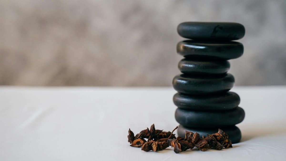 A stack of smooth stones balanced with aromatic star anise on a white surface, creating a serene atmosphere.