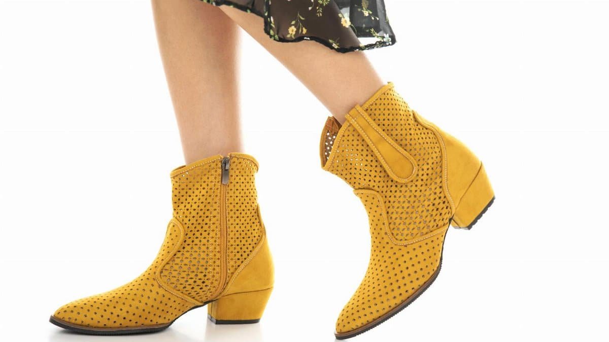 Fashionable yellow ankle boots paired with a floral dress on a clean white background, showcasing trendy footwear design.