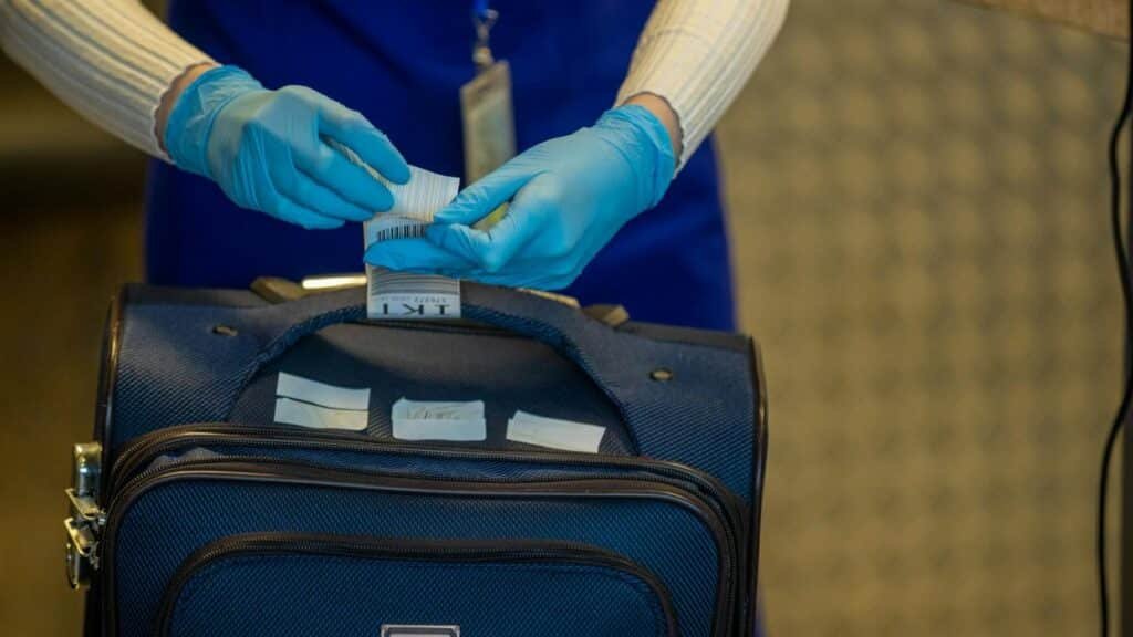 Close-up of airport security process with gloved hands inspecting luggage tags.