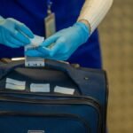 Close-up of airport security process with gloved hands inspecting luggage tags.