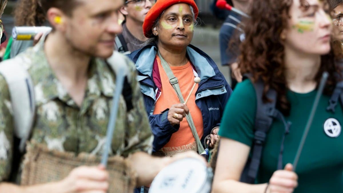 A dynamic street protest with diverse adult participants playing drums, showcasing activism.