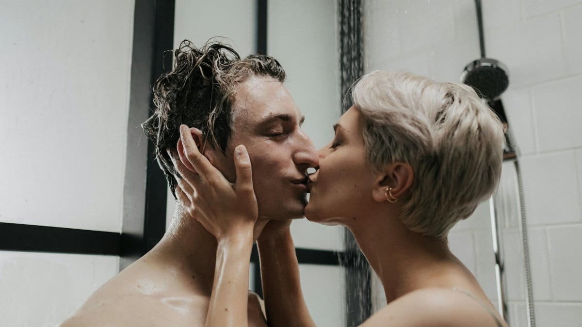 A passionate moment between a couple sharing a kiss in the shower, highlighting love and intimacy.