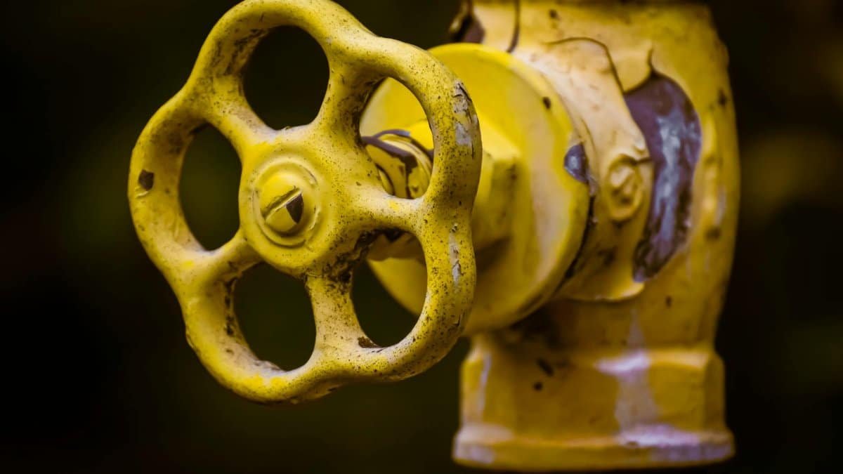 Close-up view of a rusty yellow shut-off valve, emphasizing industrial wear.