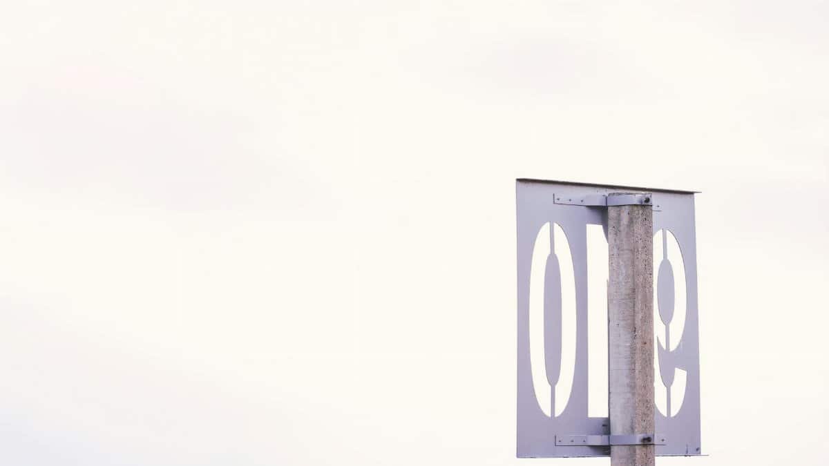 A simple and minimalist street sign displaying the number one against a clear sky.