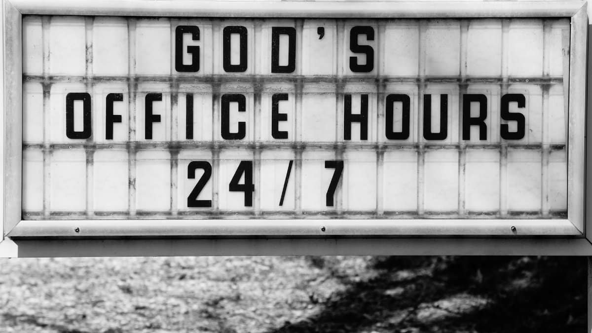 Monochrome photo of a church sign reading 'God's Office Hours 24/7' in Raleigh, NC.