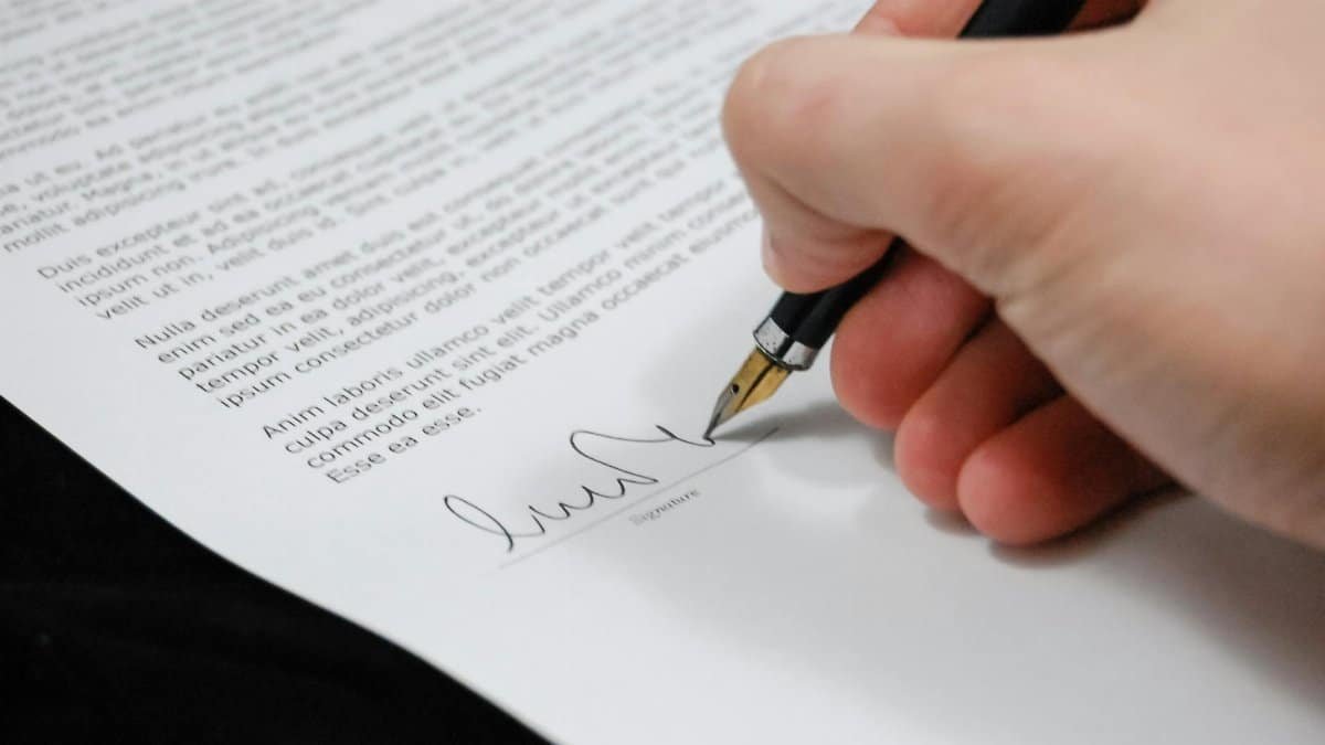 Close-up of a hand signing a legal document with a fountain pen, symbolizing signature and agreement.