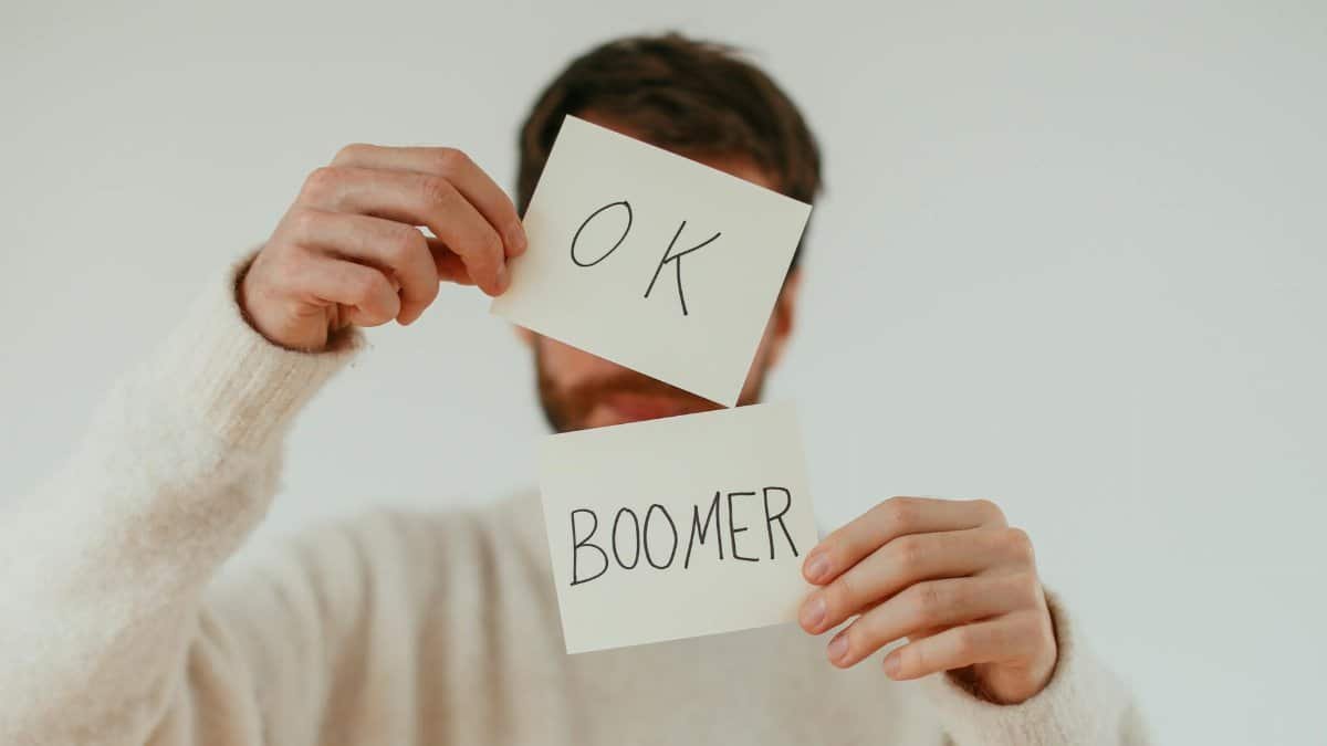 A person holding two cards with 'OK Boomer' written in bold text.