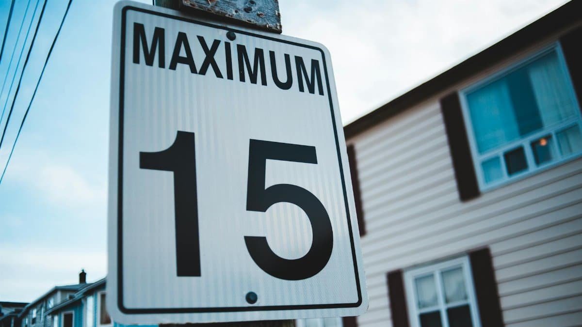 Regulatory road sign with Maximum inscription and number 15 against house facade in city in daytime