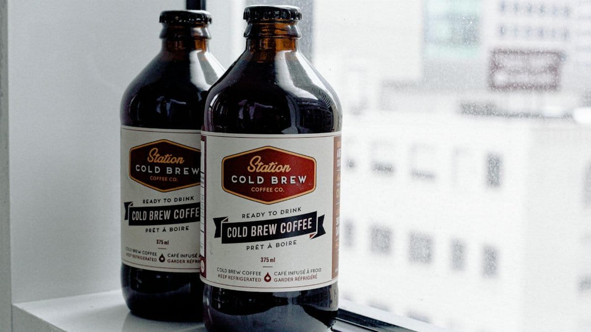 Two glass bottles of cold brew coffee placed on a window ledge, ready to drink.