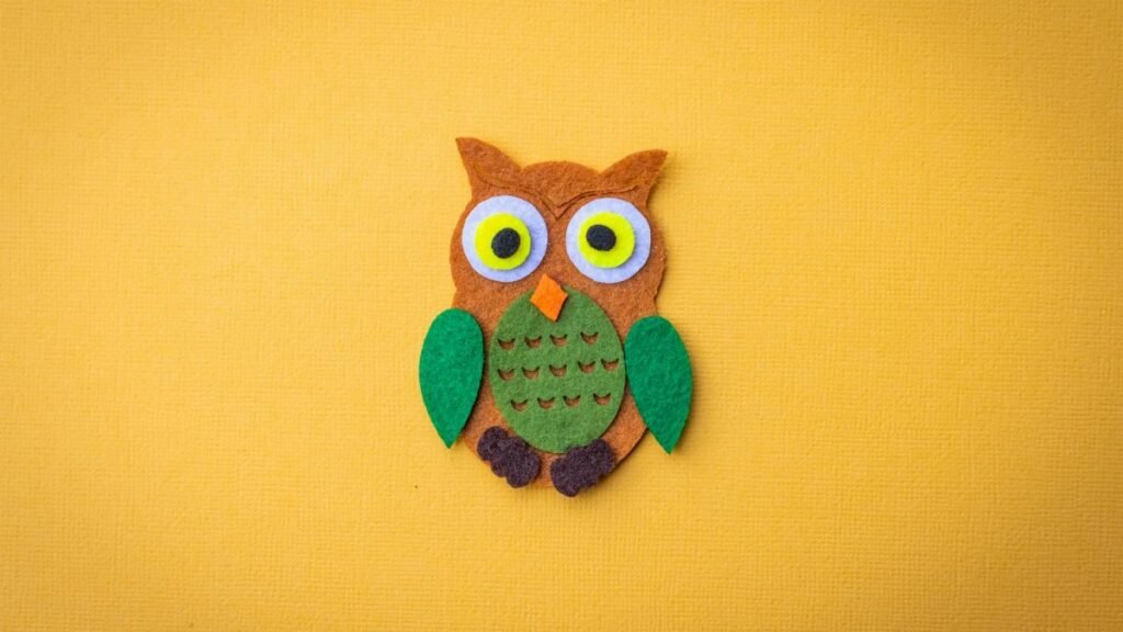 Bright felt owl craft on a vivid yellow backdrop, ideal for design projects.