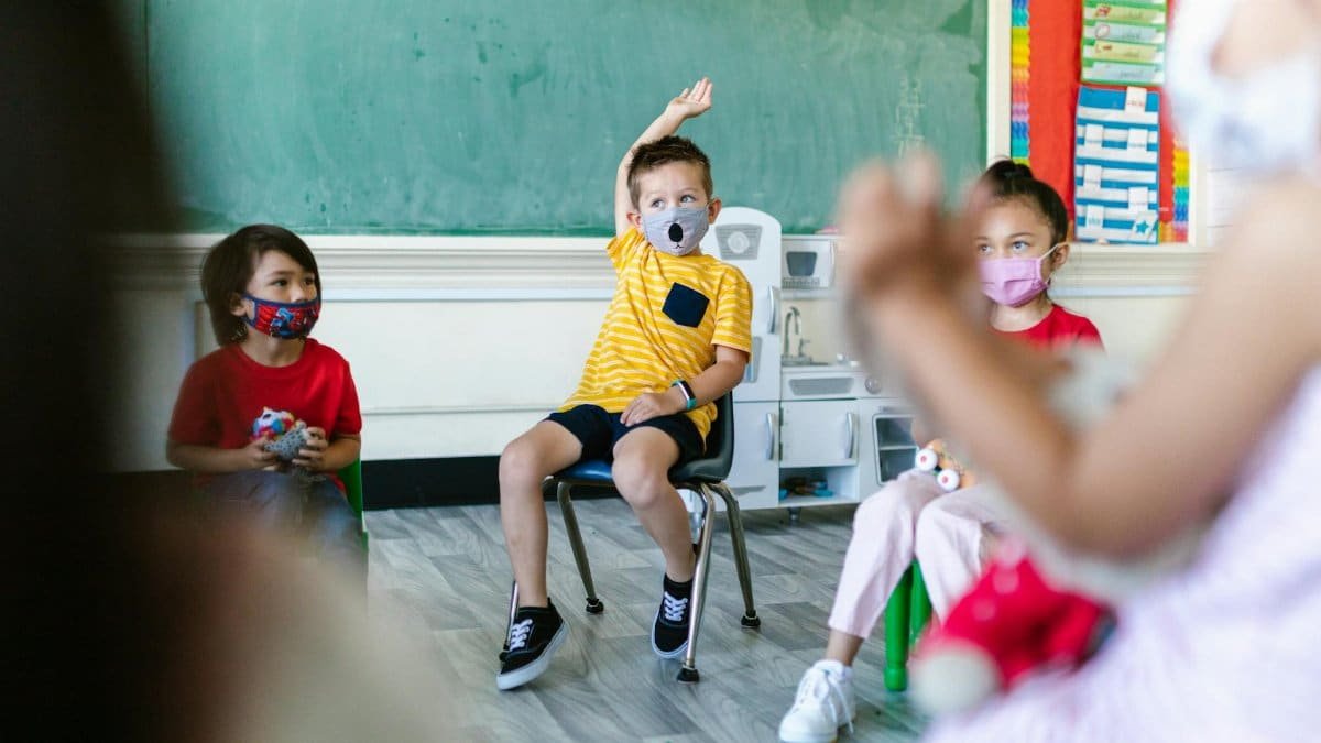 Preschool children wearing face masks participate in classroom activities, adapting to new normal routines.