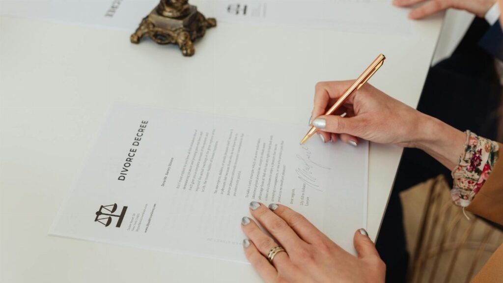 Close-up of hands signing a divorce decree document on a desk, showcasing legal process.