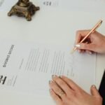 Close-up of hands signing a divorce decree document on a desk, showcasing legal process.