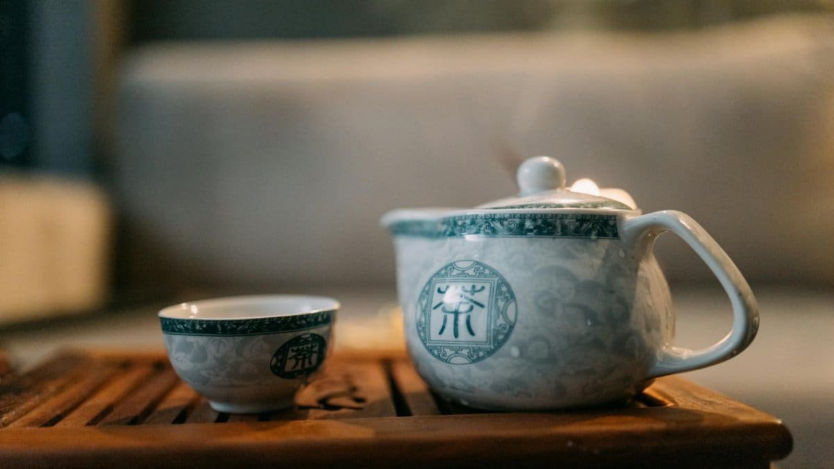 Elegantly designed porcelain teapot and cup set on a wooden tray, perfect for a serene tea ritual.