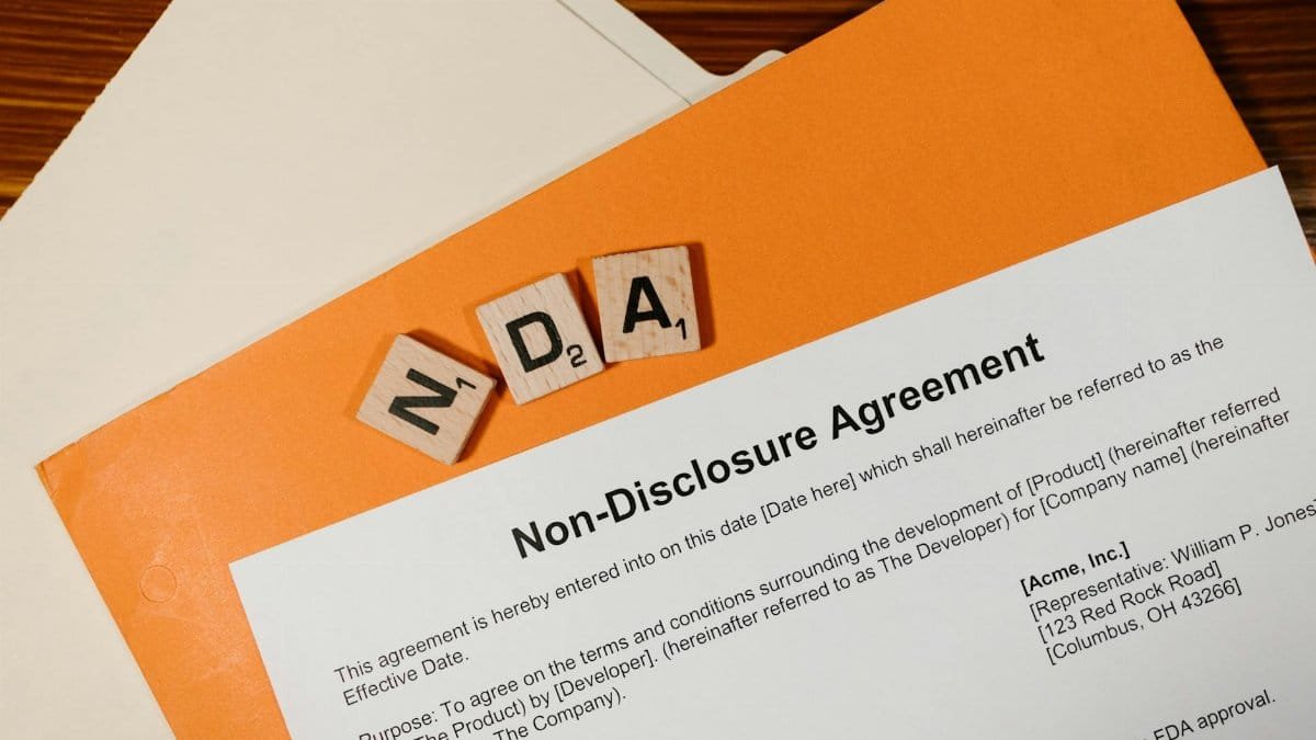 Top view of a Non-Disclosure Agreement with NDA in Scrabble tiles, emphasizing confidentiality.
