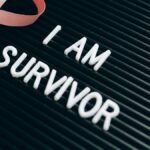 Breast cancer survivor message with pink ribbon and empowering text on board.