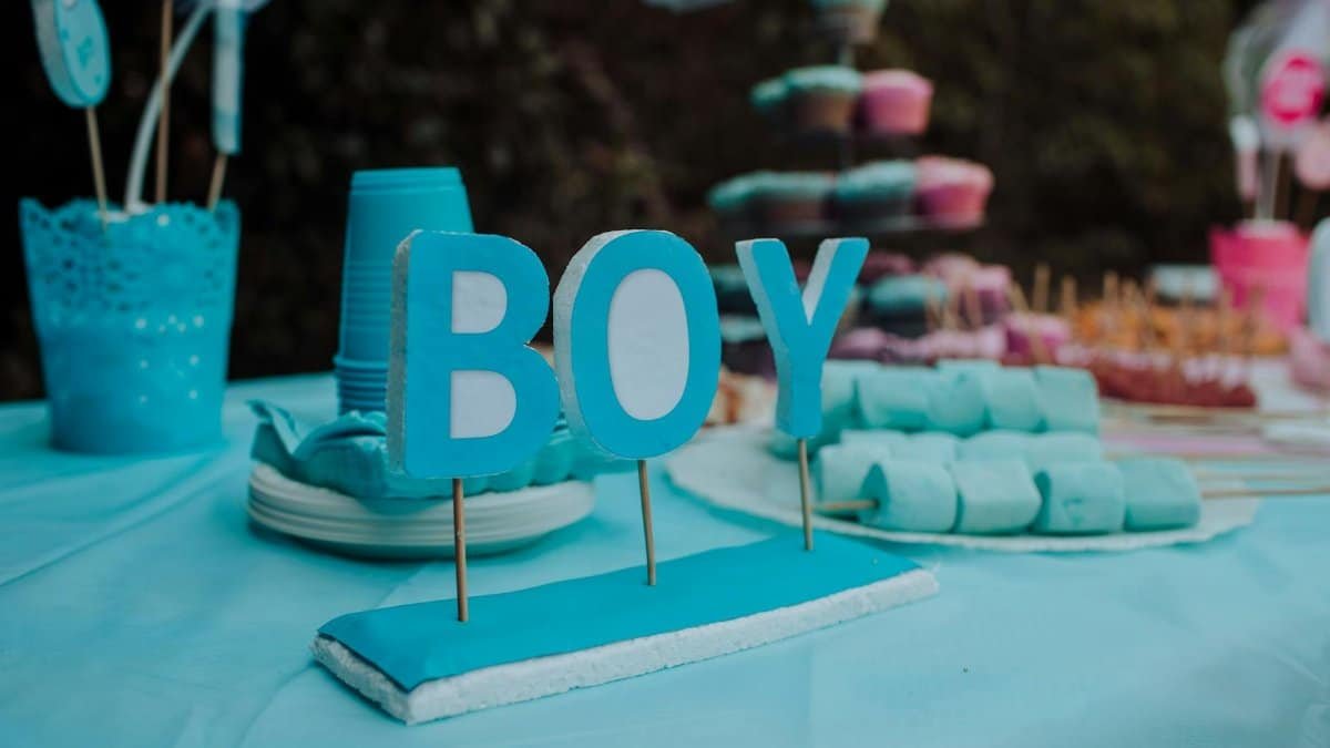 Blue-themed baby gender reveal party with decorations, indicating a boy. Festive atmosphere with sweets and decor.