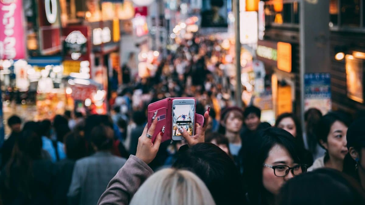 Vibrant street scene in a busy city market with diverse crowds and bright neon signage.