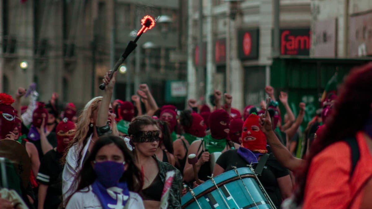 Empowered women marching with drums and masks in Valparaíso street event.