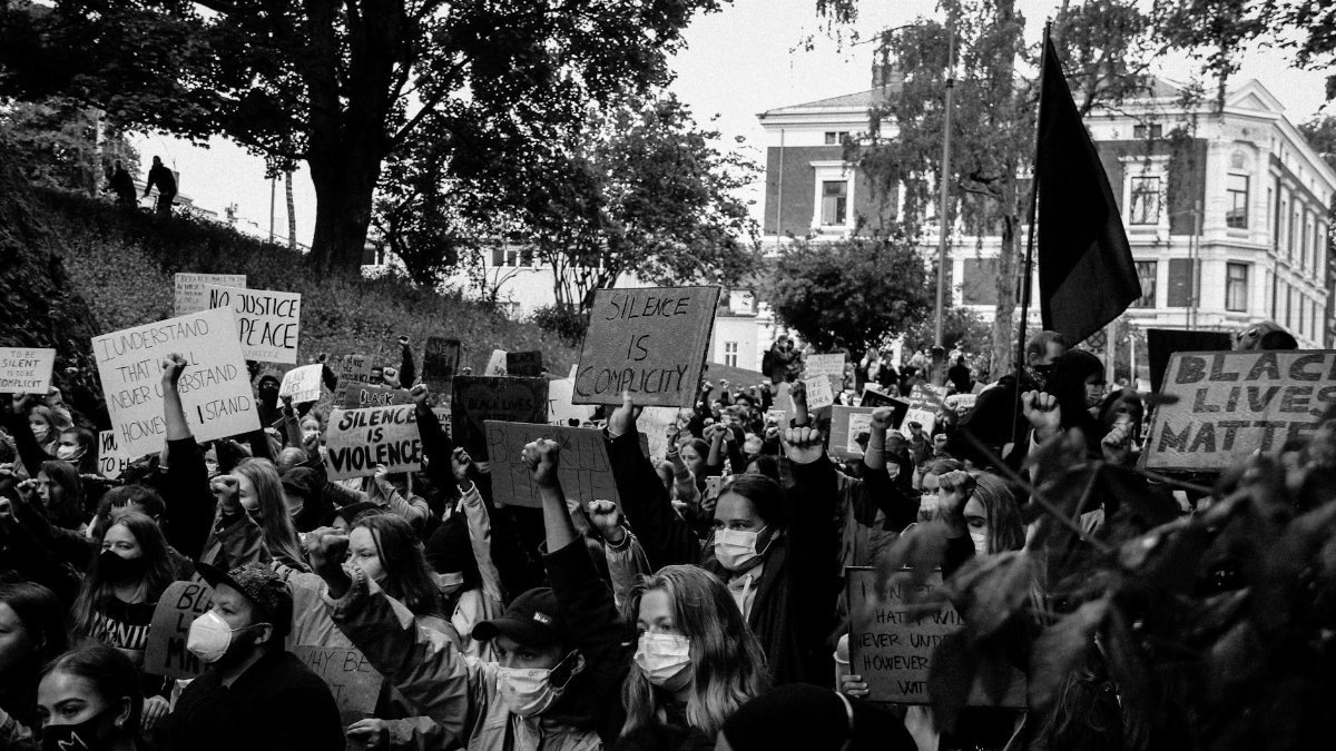 A powerful black and white image of a Black Lives Matter protest with a large crowd holding signs.