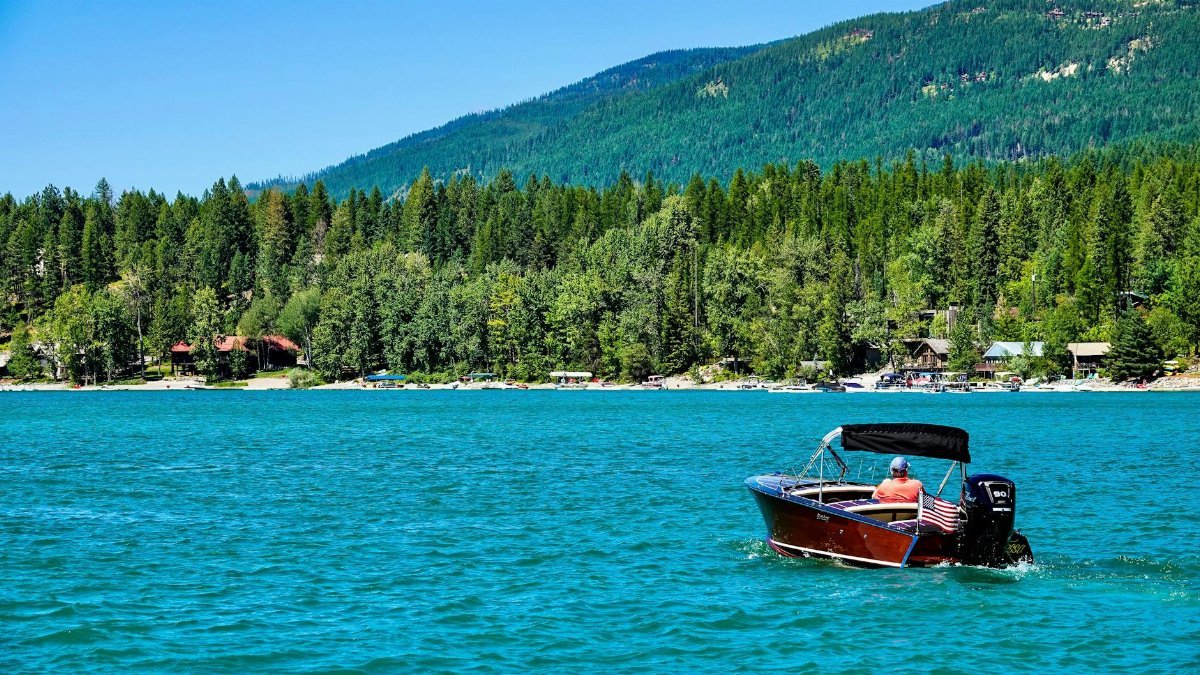 Enjoy leisure boating on serene Whitefish Lake with lush mountain views.