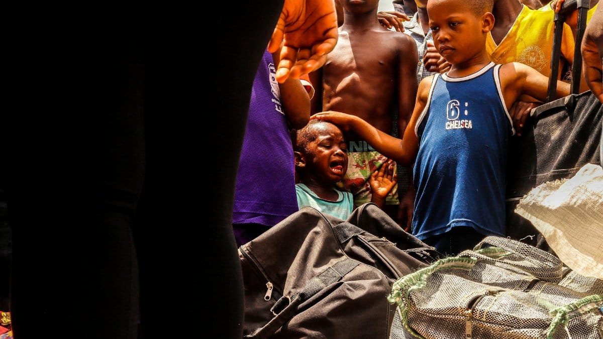A group of children gather for community service, displaying diverse emotions outdoors.