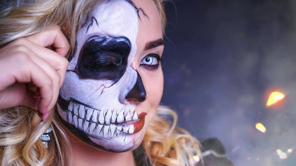 Eye-catching Halloween makeup featuring a half skull design on a woman's face.