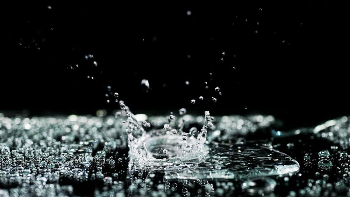 Dynamic high-speed photo capturing water droplets splashing on a black background.