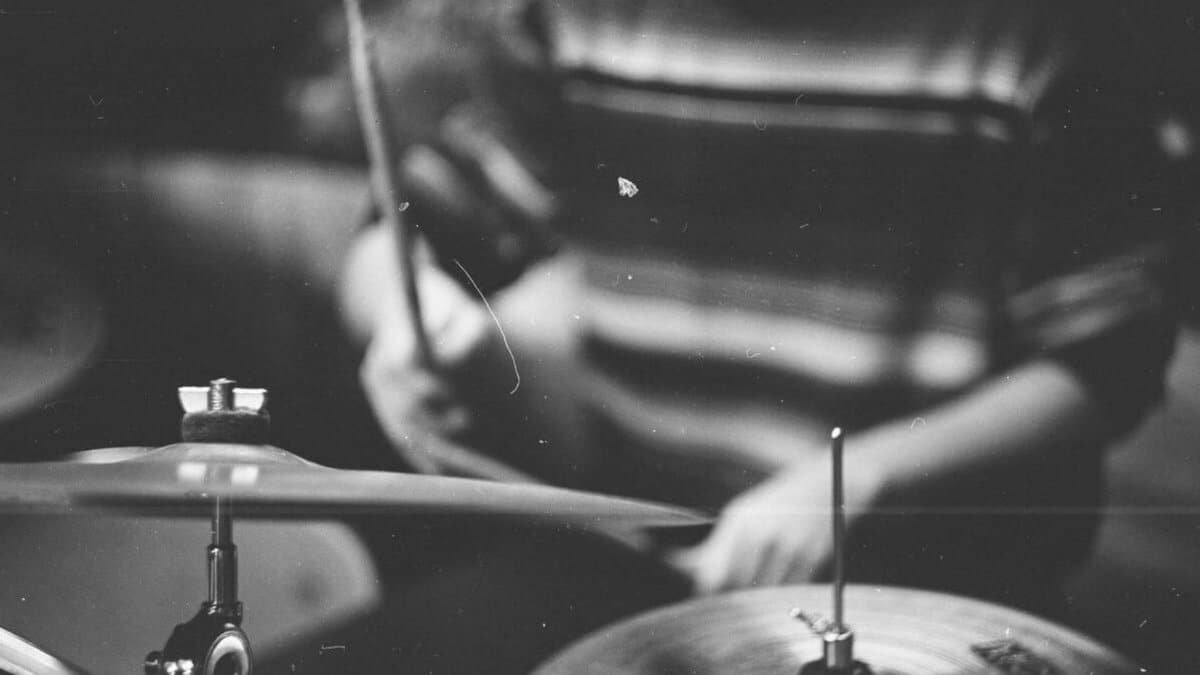 Artistic black and white photo of a drummer playing cymbals with selective focus.