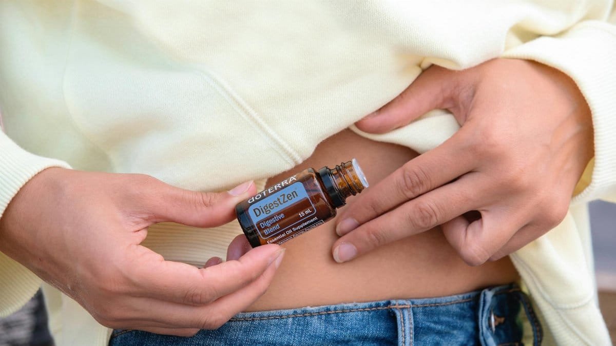 Close-up of hands applying doterra's DigestZen essential oil for indigestion.
