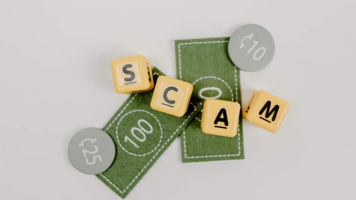 Yellow dice spelling 'Scam' on fake currency, representing financial deception.