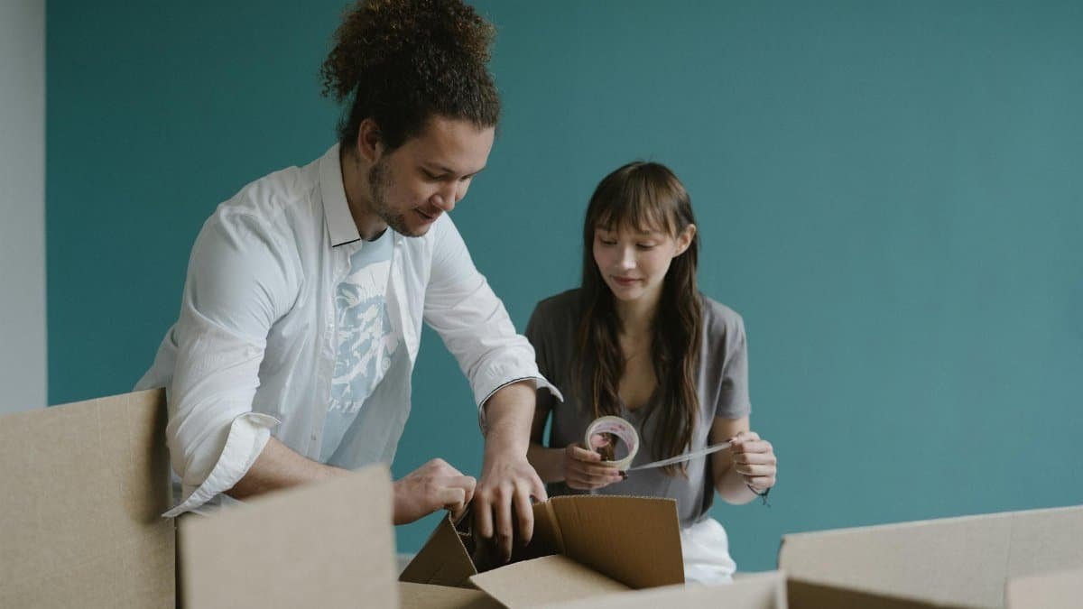 Young couple smiling while unpacking boxes in their new apartment. Moving in and home concept.