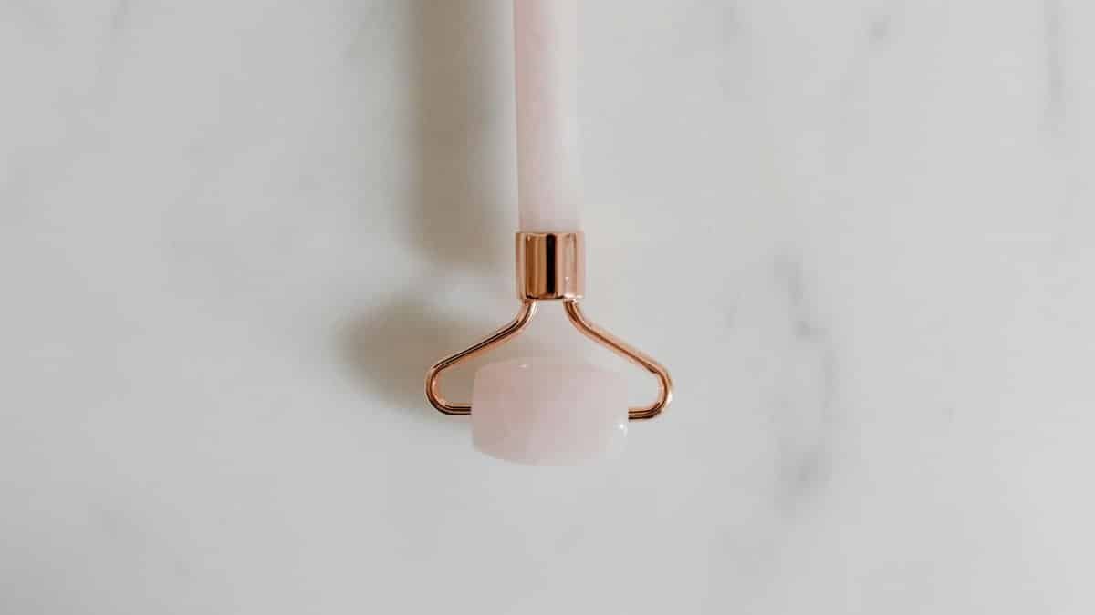 A close-up of a rose quartz facial roller on a marble surface, symbolizing luxury skincare.