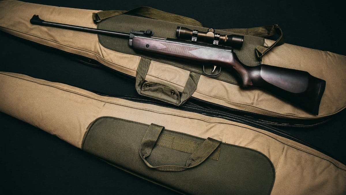 Close-up of a hunting rifle with a scope on a carrying bag, showcasing firearms and hunting gear.